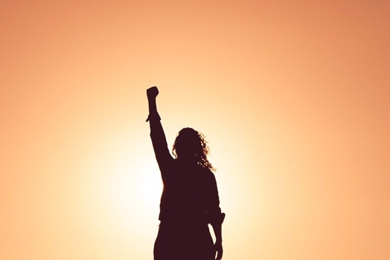 Empowered woman silhouette celebrating health and wellness at sunset