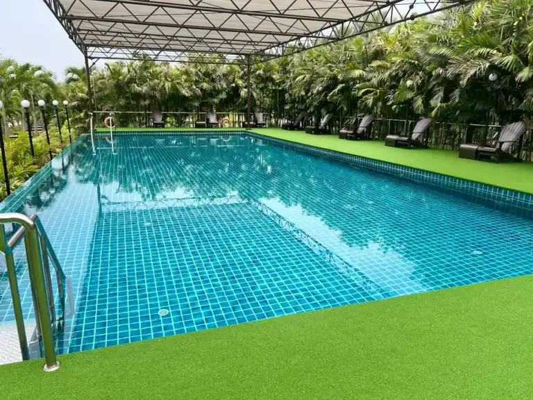 Relaxing outdoor swimming pool surrounded by lush tropical plants at Bangkok Health Service - Swimmingpool Sanpudard Wellness Club