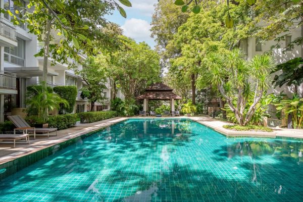 Long tropical swimming pool surrounded by trees beside the group's Bangkok wellness accommodation