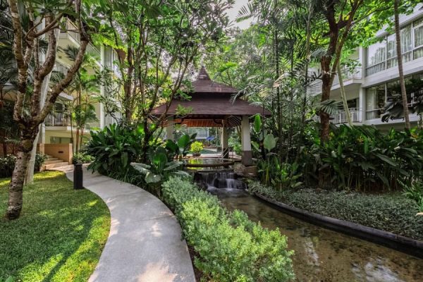 Curving garden path beside water, trees and low-rise accommodation buildings
