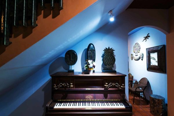 Antique blue piano beneath a staircase in a private creative wellness retreat setting