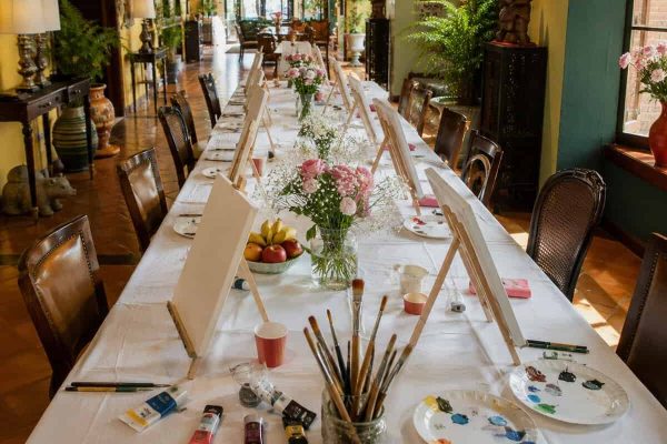 Round table prepared with paints, brushes and paper for a small creative wellness group