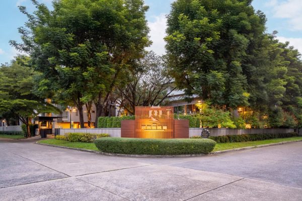 Tree-lined entrance with landscaped gardens and a discreet accommodation sign