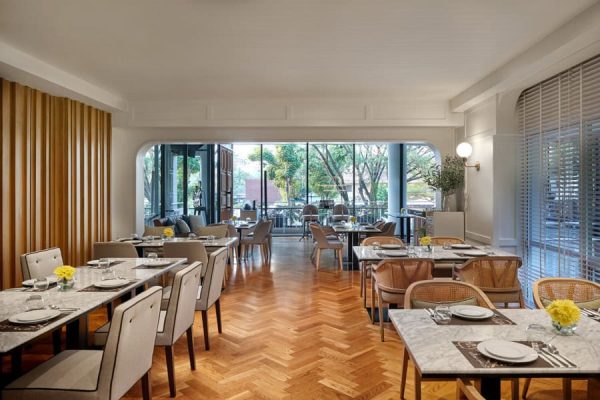 Spacious dining room with marble tables, warm wood floors and garden views