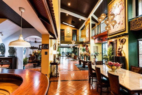 Long teak dining corridor beside the open atrium of a private group wellness retreat venue