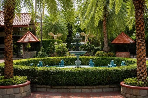 Fountain surrounded by palms and greenery in a private tropical retreat garden