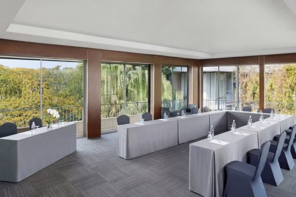 Garden-view meeting room arranged with white tables in a U-shape