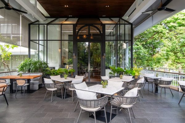 Modern open-air dining terrace with marble tables, greenery and garden views