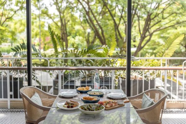 Covered balcony dining table overlooking large tropical trees and gardens