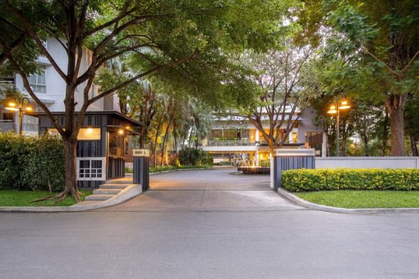 Tree-lined driveway and warmly lit hotel entrance in the early evening