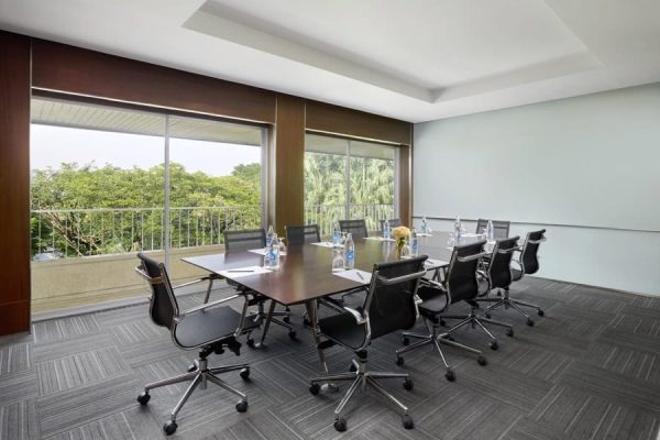 Private boardroom with a long meeting table, office chairs and green garden views