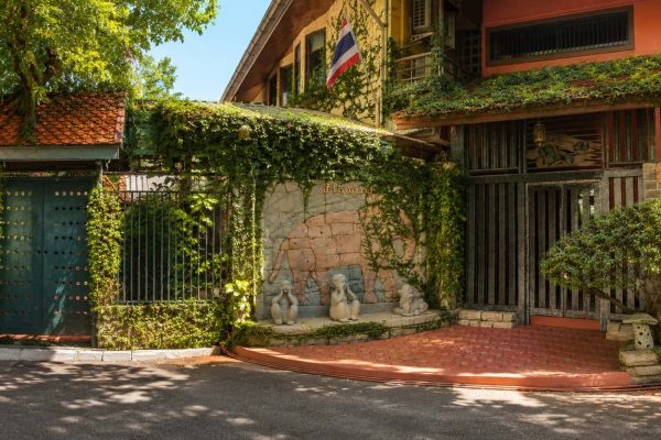 Vine-covered gates and elephant relief wall at the entrance to a private Bangkok wellness retreat