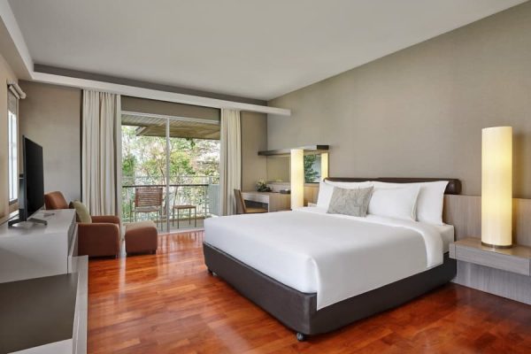 Spacious private guest room with a king bed, balcony and tropical garden view