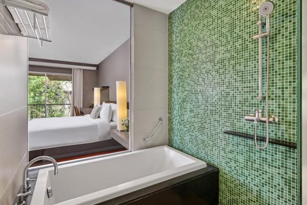 Private bathroom with a bathtub and separate green-tiled shower beside the guest room