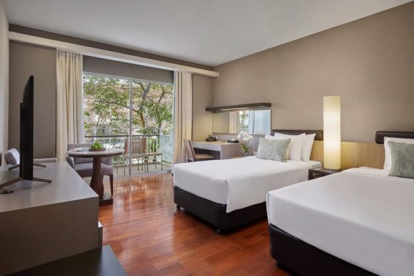 Bright twin guest room with two beds, a balcony and garden views