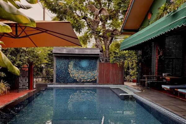 Small private pool with a blue fish mosaic, tropical plants and shaded loungers
