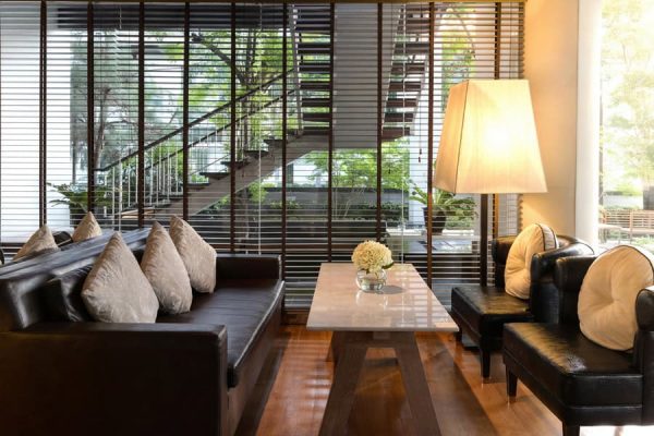 Comfortable lounge seating beside tall windows and tropical garden views