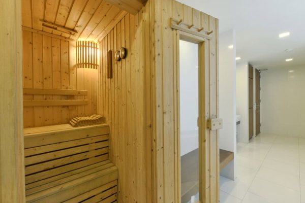 Wood-lined sauna with benches and warm wall lighting