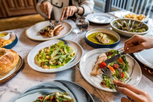 Group sharing colourful salads, vegetables and plated dishes around a dining table