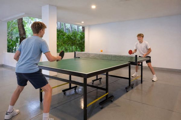 Two guests playing table tennis in a bright recreation room