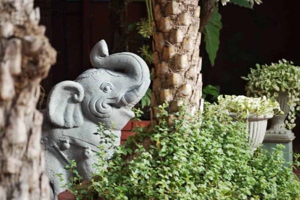 Carved elephant sculpture among tropical plants at a private Bangkok retreat venue