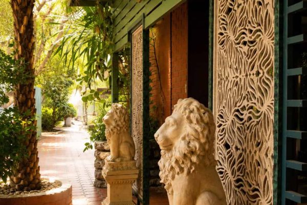 Covered garden walkway with carved stone lion guardians and tropical plants