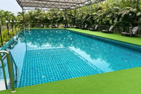 Relaxing outdoor swimming pool surrounded by lush tropical plants at Bangkok Health Service - Swimmingpool Sanpudard Wellness Club
