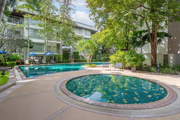 Outdoor pool and circular jacuzzi surrounded by trees and guest accommodation