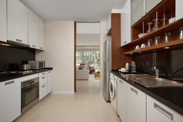 White kitchenette with refrigerator, microwave, hob and washing machine in a guest suite