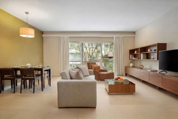 Large apartment-style living and dining area with windows overlooking tropical greenery