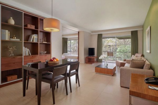 Apartment-style suite with dining table, sofa, work area and garden-facing windows